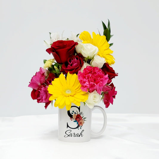 This uplifting floral arrangement of fresh flowers expertly arranged in a reusable coffee mug.