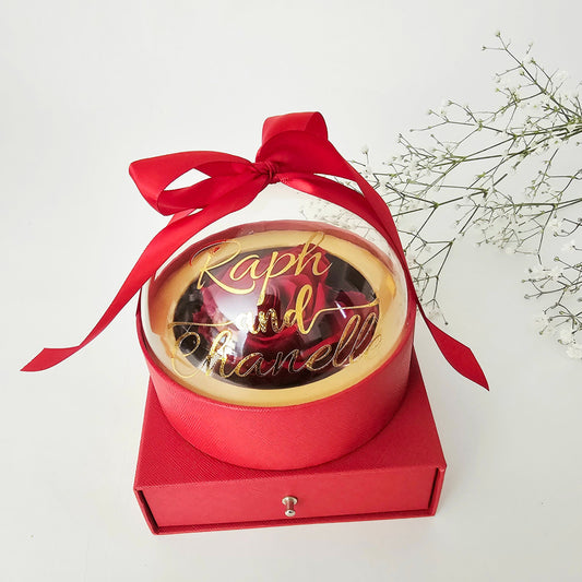 A luxurious, round, globe-shaped box featuring a transparent, customizable lid centered with a single eternal rose. Use the discreet pull-out drawer below to hide and present your special gift—perfect for jewelry, chocolates, or a proposal ring.