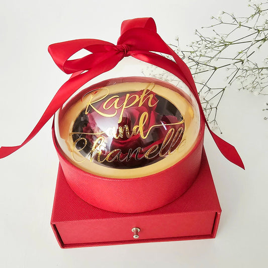 A luxurious, round, globe-shaped box featuring a transparent, customizable lid centered with a single eternal rose. Use the discreet pull-out drawer below to hide and present your special gift—perfect for jewelry, chocolates, or a proposal ring.