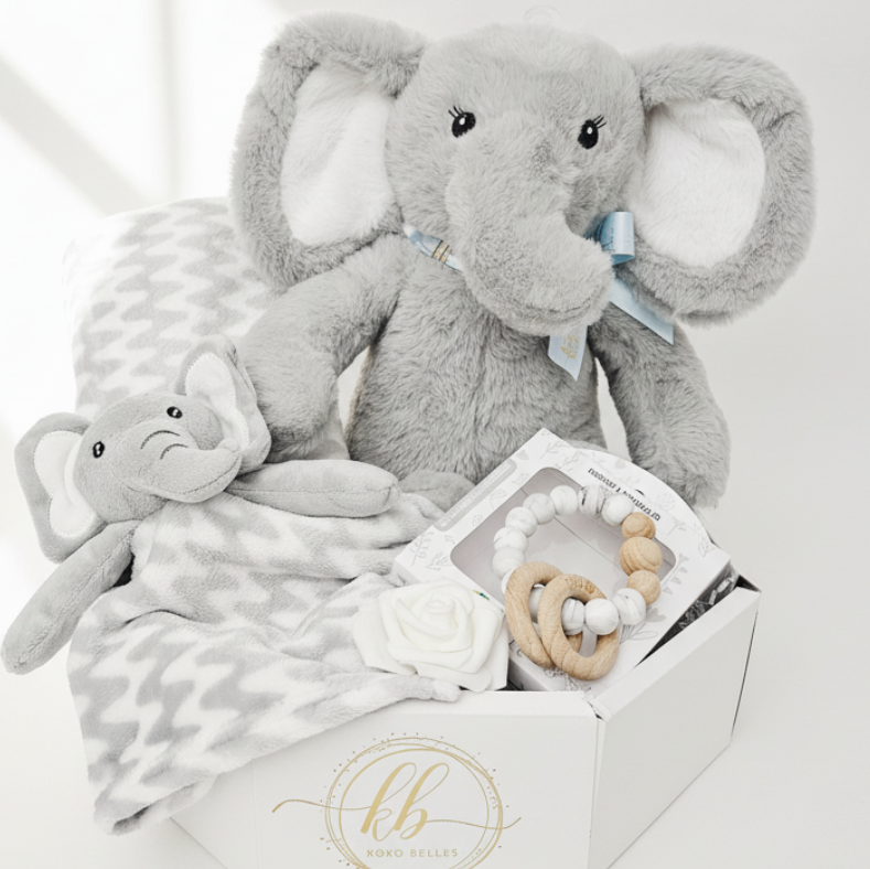 Gray plush elephant toy with a baby blanket and teething ring on a white background