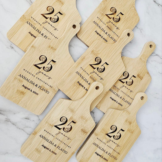 Set of five personalized wooden cutting boards with '25 years' engraving on a marble surface.