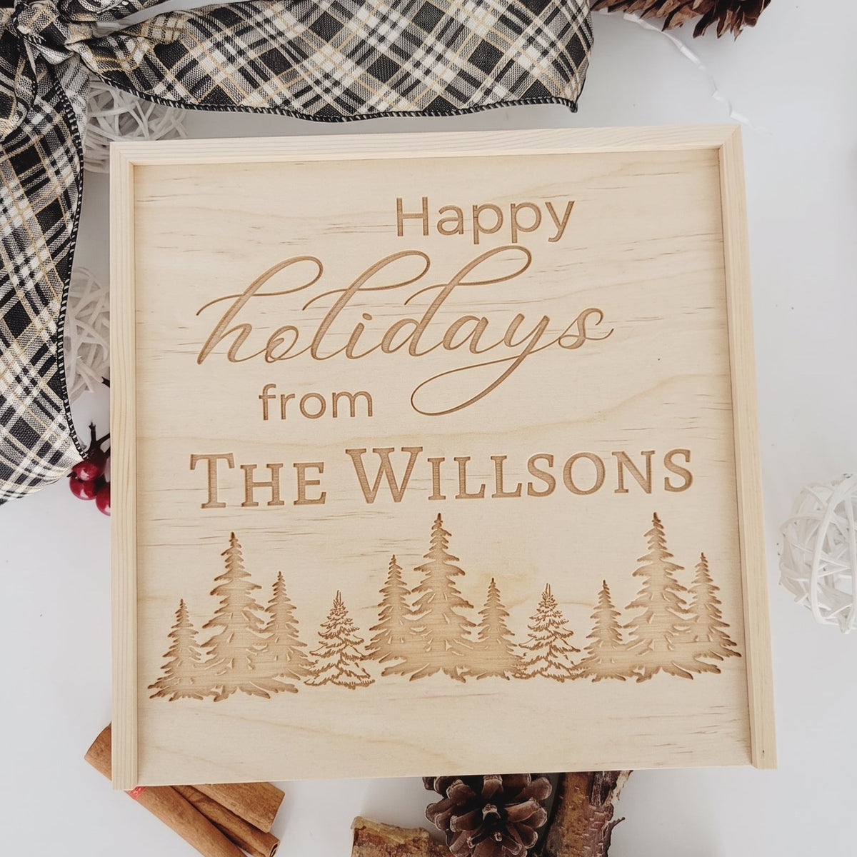 Personalized wooden holiday keepsake box with laser-engraved pine tree forest and custom family last name with Happy Holidays message.