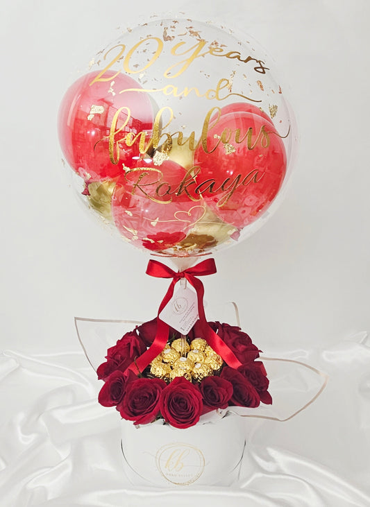 Luxury birthday gift box featuring a personalized clear bubble balloon, red roses, and chocolates.
