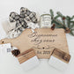 Custom engraved wooden cutting board displayed with a candle, coasters, and a cozy throw, as a rustic housewarming gift