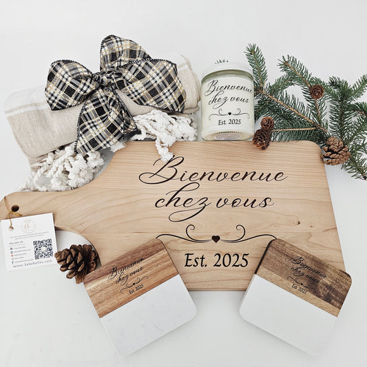 Custom engraved wooden cutting board displayed with a candle, coasters, and a cozy throw, as a rustic housewarming gift