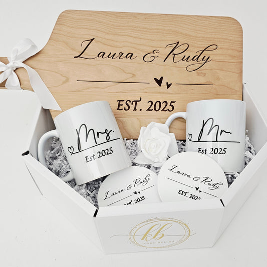 Personalized wooden cutting board and ceramic mugs with 'Mr' and 'Mrs' designs, set against a white background.