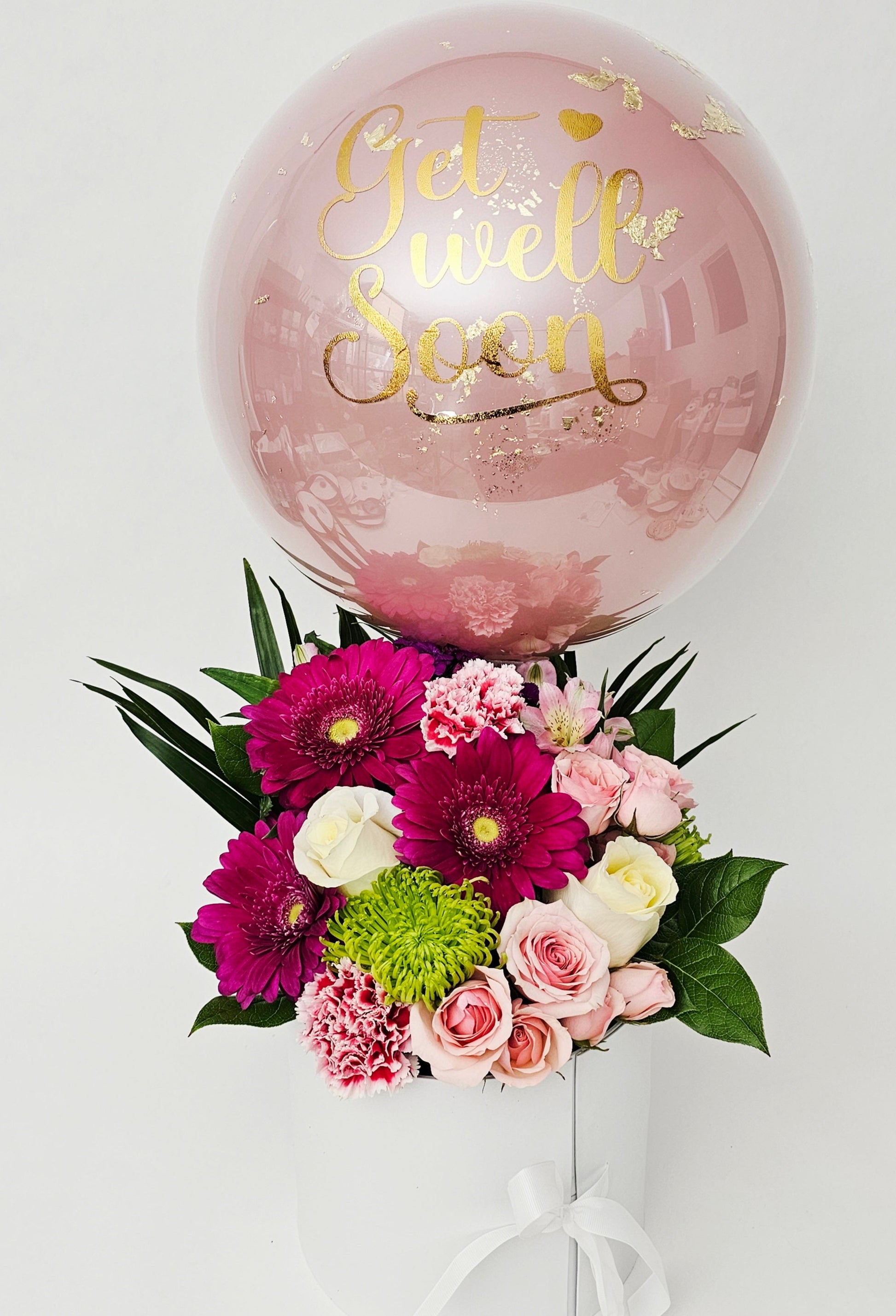 Pink balloon with 'Get well Soon' text above a bouquet of flowers on a white background