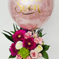 Pink balloon with gold text and a bouquet of flowers on a white background