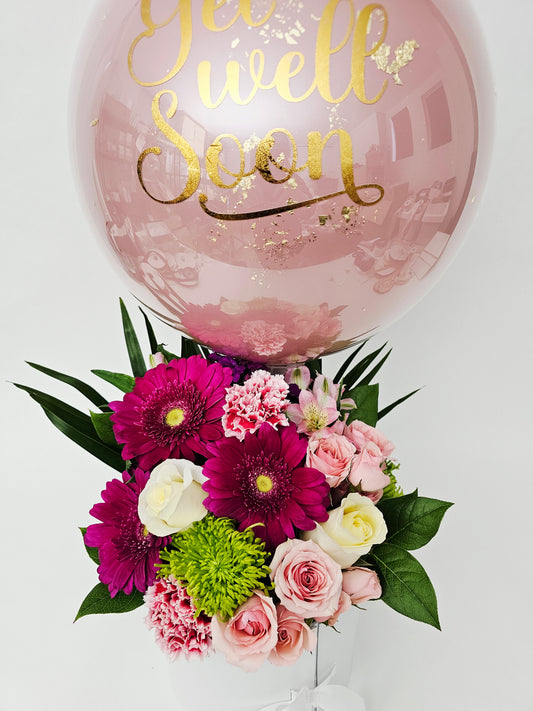 Pink balloon with gold text and a bouquet of flowers on a white background