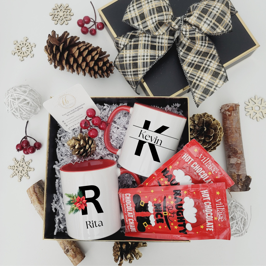 Gift set with personalized mugs and hot chocolate packets on a decorative surface.