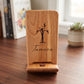 Wooden phone and tablet stand featuring a custom laser-engraved floral initial T and the name Tamara, resting on a clean wooden desk.