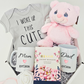 Baby-themed gift set with t-shirt, mug, tea, and plush toy on a light background