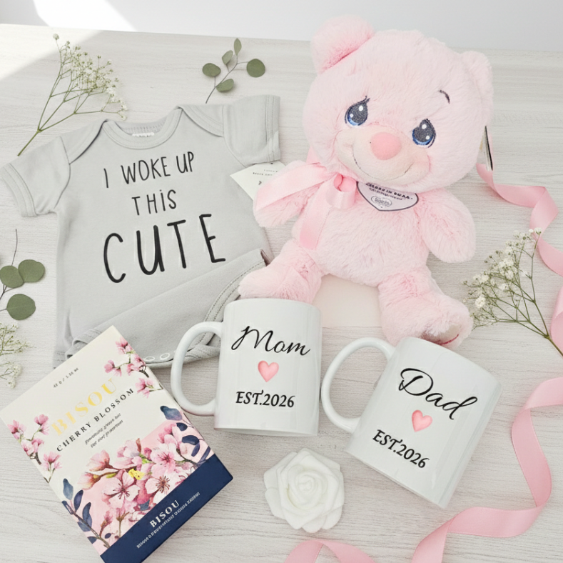 Baby-themed items including a pink plush toy, baby onesie, mugs for 'Mom' and 'Dad', and a box of gourmet tea.