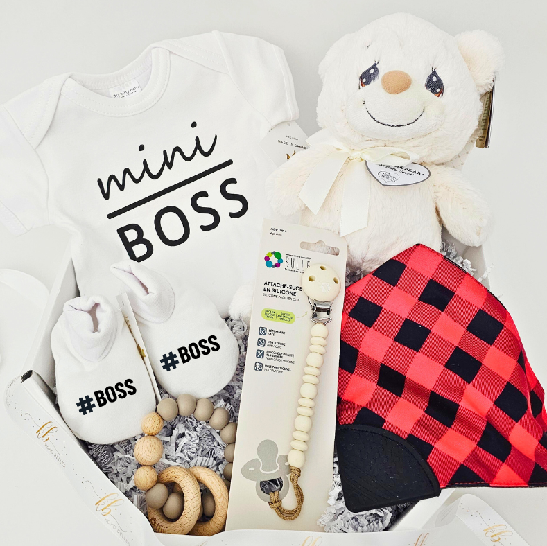 Baby gift set with 'mini BOSS' onesie, plush toy, and other items on a light gray background