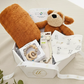 Baby gift box with plush toys, bib, and other items on a light background
