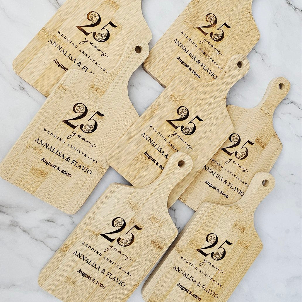 Set of five personalized wooden cutting boards with '25 years' engraving on a marble surface.