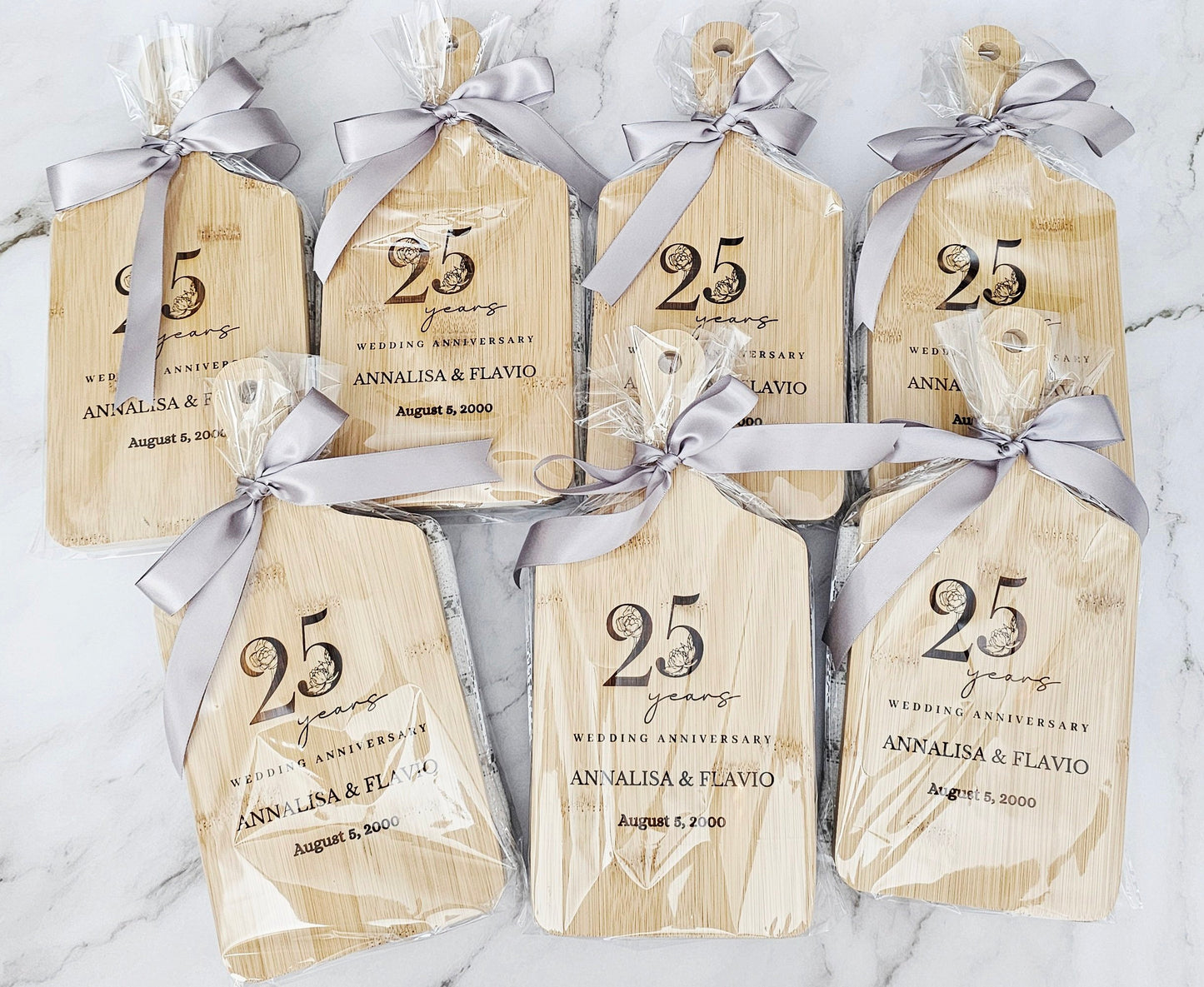 Wooden tags with '25 years wedding anniversary' text and ribbons on a marble surface