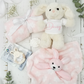 Baby gift set with plush bunny, blanket, and toys on a light wooden surface.