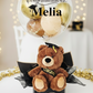 Graduation-themed gift with teddy bear, balloon, and 'Congratulations Melia' text 