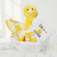 Baby gift set with plush duck, bib, and socks in a box on a white background