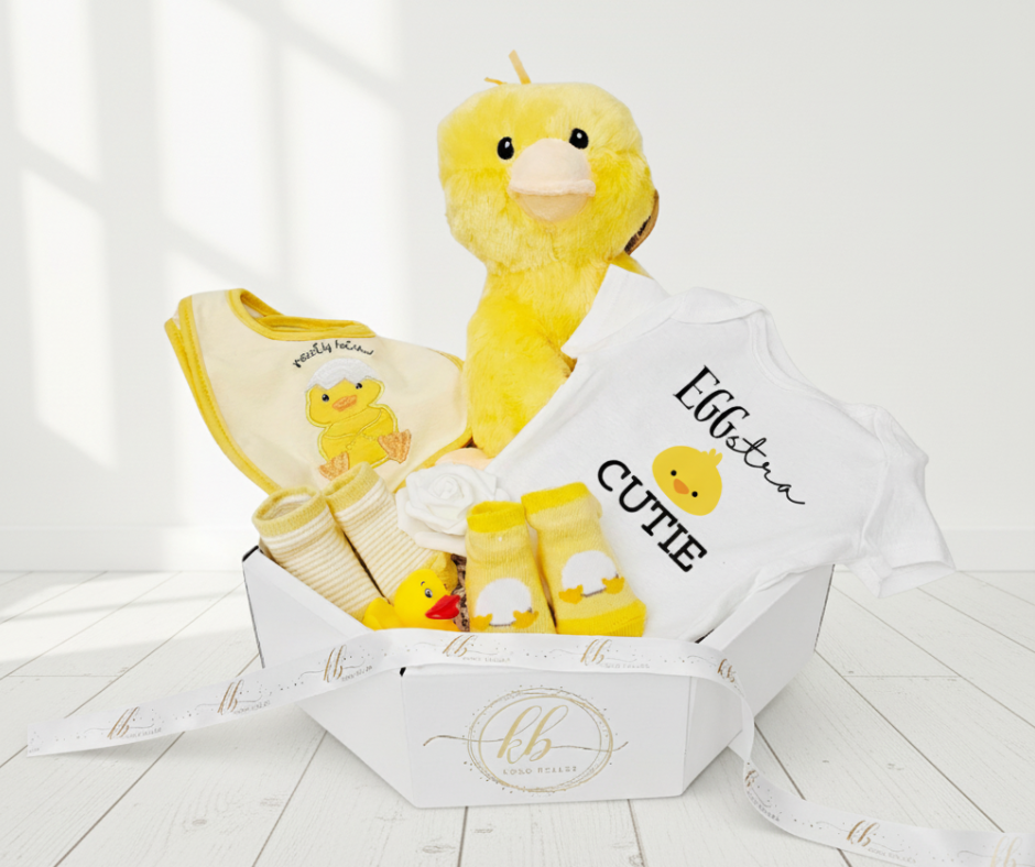 Baby gift set with plush duck, bib, and socks in a box on a white background