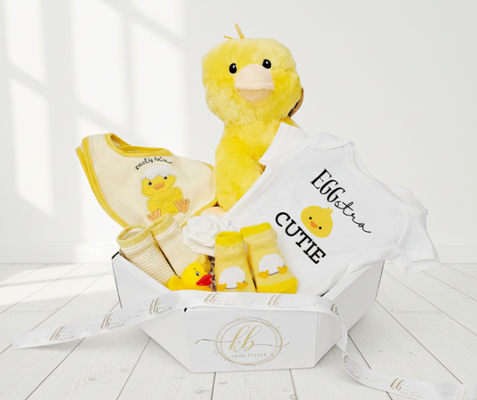 Baby gift set with plush duck, bib, and socks in a box on a white background