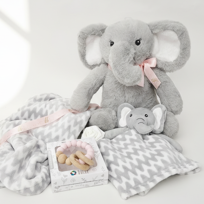 Gray elephant plush toy with a baby rattle and blanket on a white background