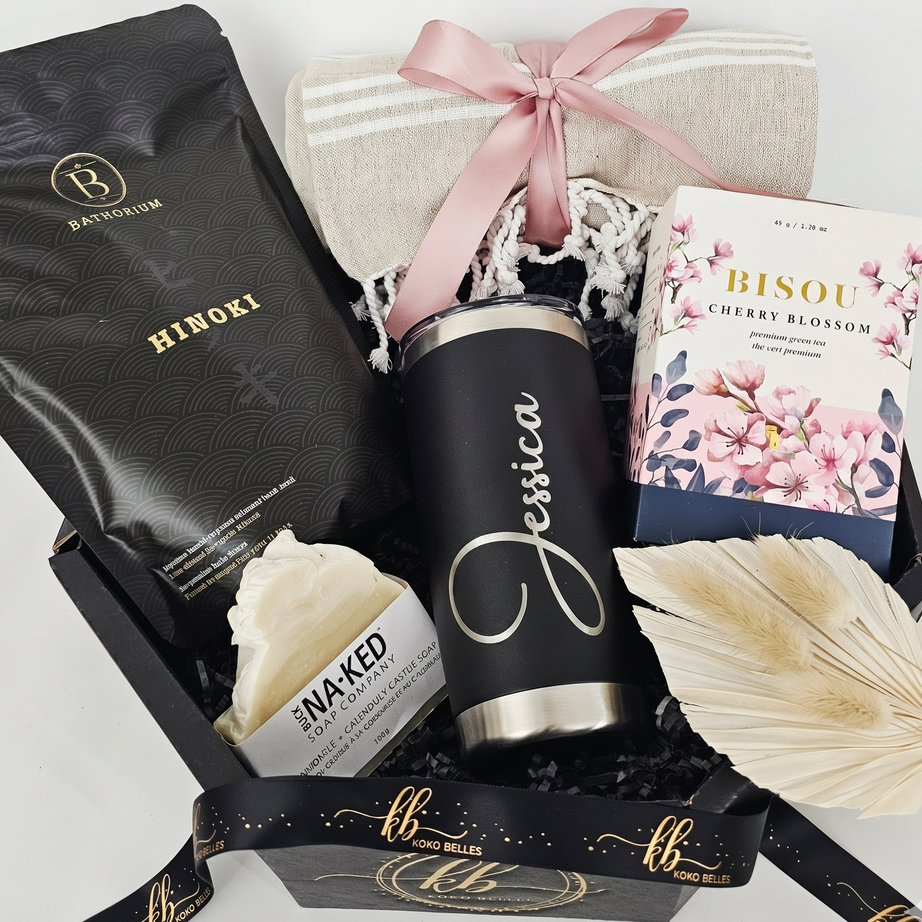 A luxury black octagonal gift box filled with a custom laser-engraved matte black tumbler featuring the name Jessica, a beige Turkish towel, Bisou Cherry Blossom green tea, Bathorium Hinoki mineral bath soak, and a handmade Buck Naked soap bar.
