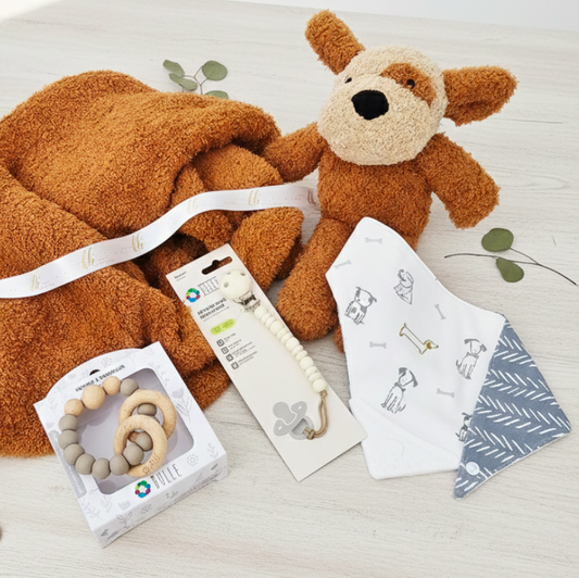 Baby product set with plush toy, blanket, and a rattle on a light surface
