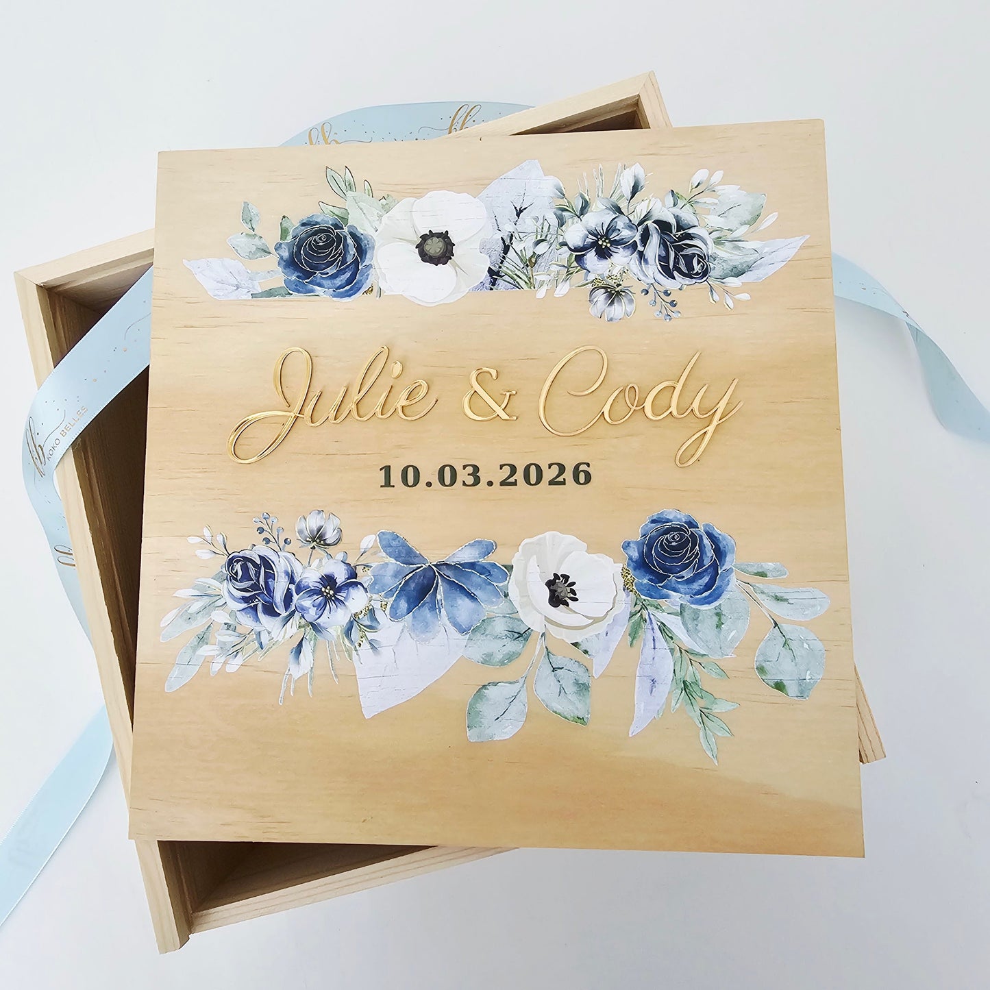 Wooden box with floral design and text, featuring blue and white flowers.