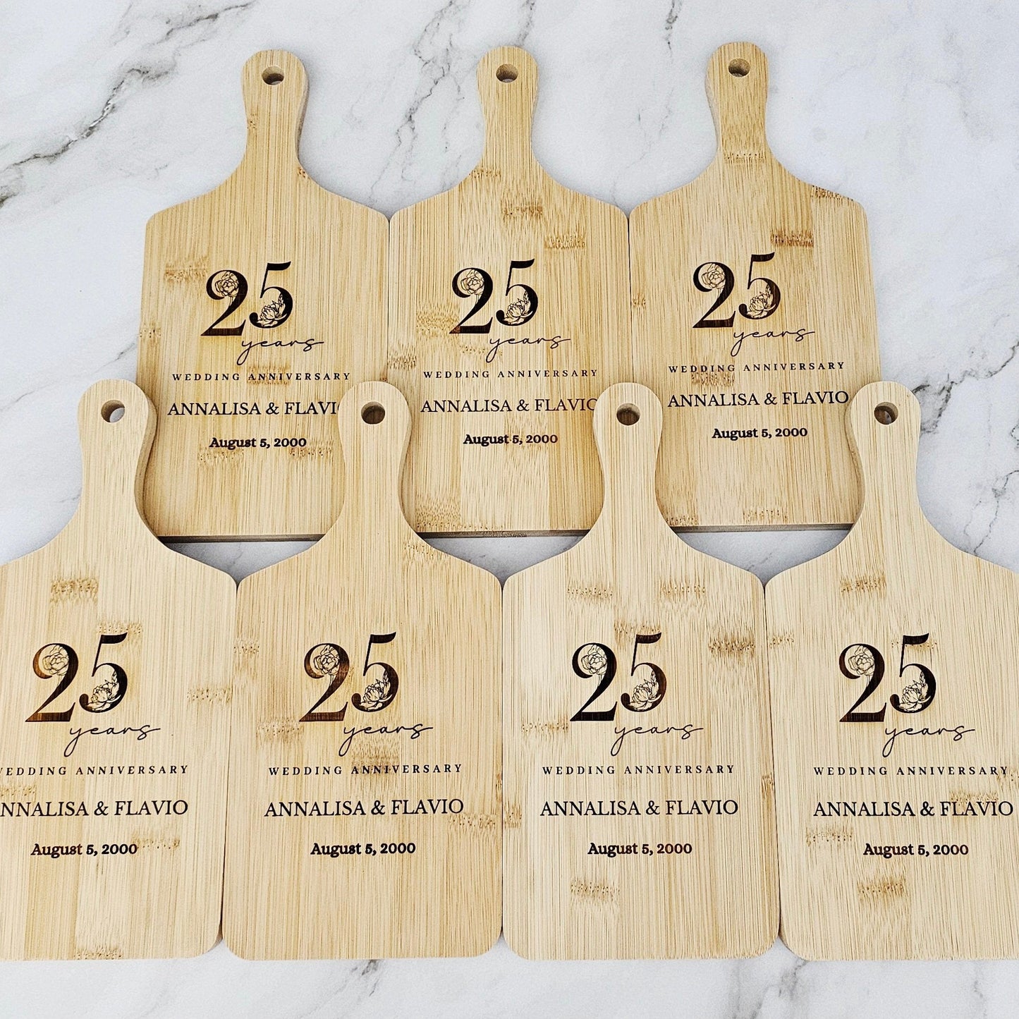 Set of six wooden cutting boards with '25 years' anniversary text on a marble background