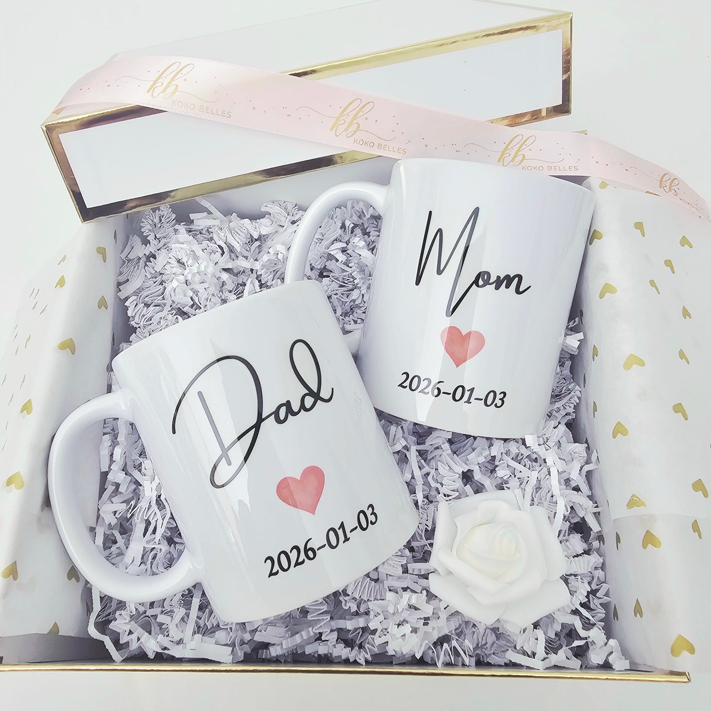 Two white mugs with 'Dad' and 'Mom' and dates in a decorative box.
