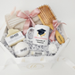 An elegant octagonal graduation gift box containing a custom mug personalized for Melissa Tremblay at the University of Montreal with a cap and diploma graphic, paired with a matching engraved hairbrush and a selection of relaxing spa products.