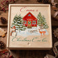 Personalized wooden Christmas Eve box with custom child's name featuring a cozy red winter cottage, snow-covered pine trees, snowman, and deer artwork.