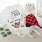 Baby gift set with teddy bear, onesie, and other items on a bed.