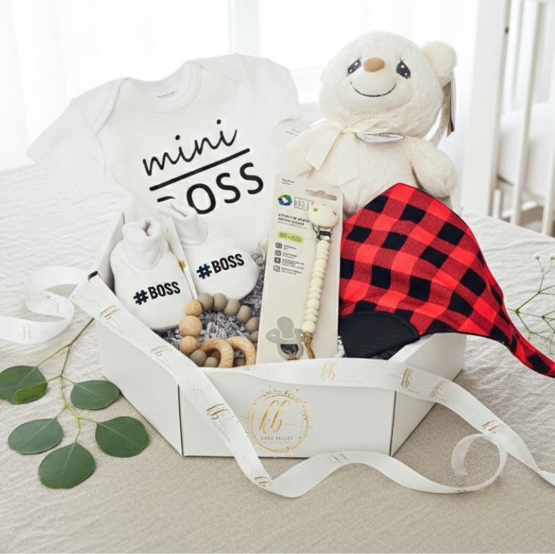 Baby gift set with teddy bear, onesie, and other items on a bed.